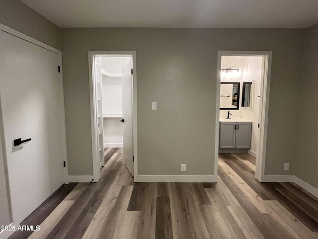 unfurnished bedroom featuring ensuite bathroom, sink, and light wood-type flooring