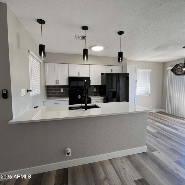 kitchen with white cabinetry, sink, pendant lighting, and black appliances