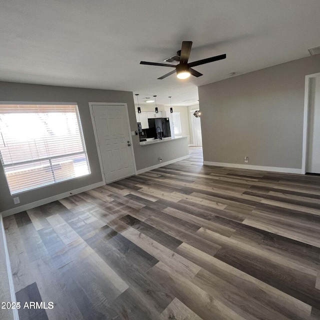 unfurnished living room featuring dark wood-type flooring and ceiling fan