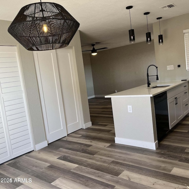 kitchen with decorative light fixtures, dishwasher, sink, kitchen peninsula, and dark wood-type flooring