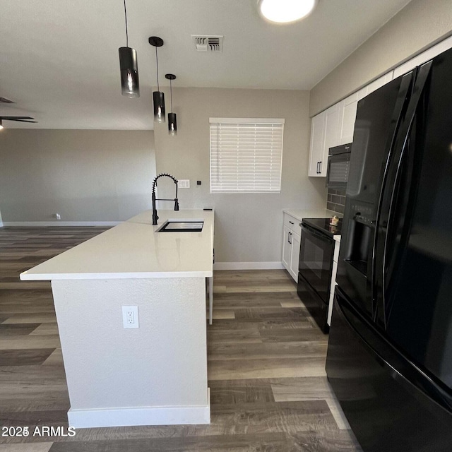 kitchen with pendant lighting, white cabinetry, sink, black appliances, and dark wood-type flooring