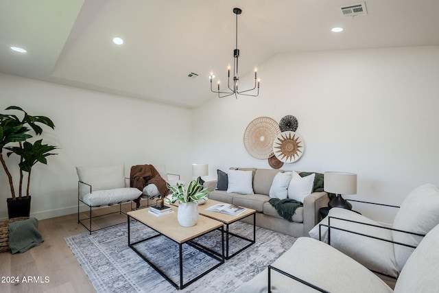 living room featuring a chandelier, vaulted ceiling, and light hardwood / wood-style flooring