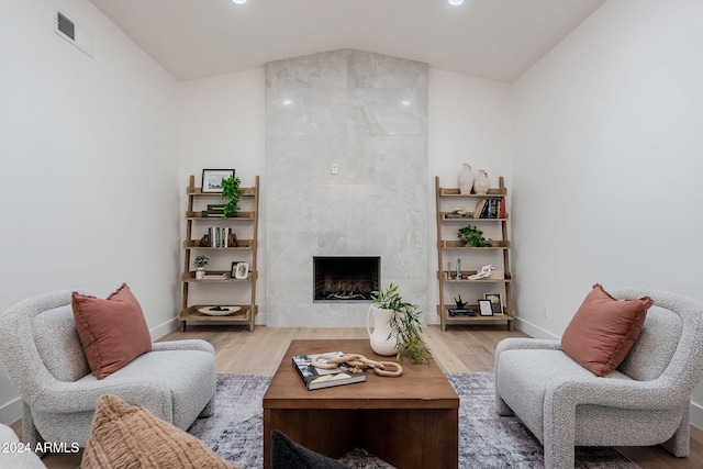 living room with a fireplace, light hardwood / wood-style flooring, and lofted ceiling