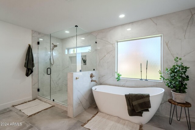 bathroom with shower with separate bathtub, a wealth of natural light, and tile walls