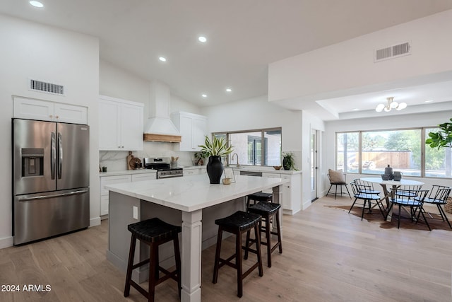 kitchen featuring white cabinetry, light hardwood / wood-style flooring, stainless steel appliances, and custom range hood