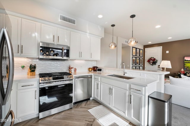 kitchen featuring kitchen peninsula, stainless steel appliances, white cabinets, and sink