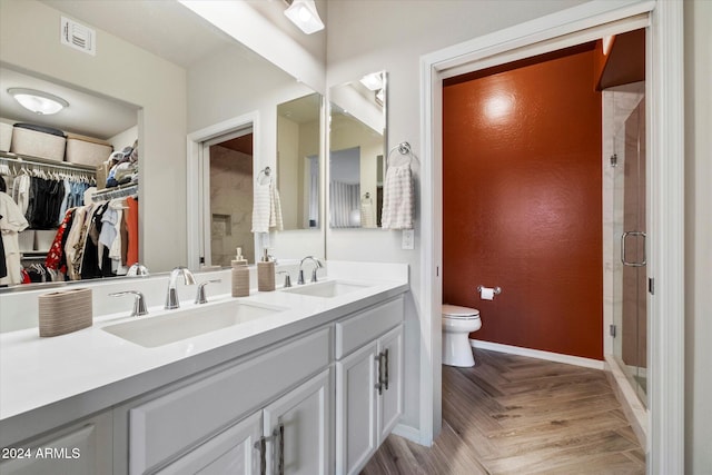 bathroom featuring parquet floors, vanity, toilet, and a shower with door