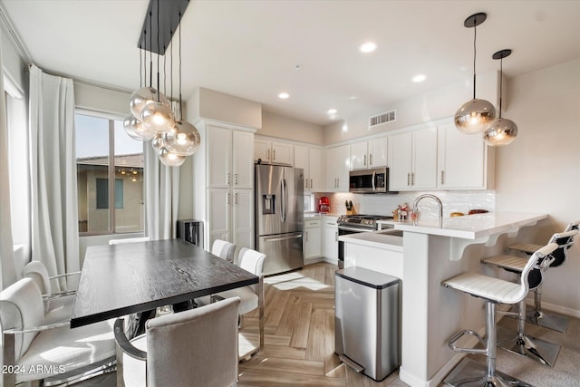 kitchen with backsplash, kitchen peninsula, appliances with stainless steel finishes, white cabinetry, and a breakfast bar area