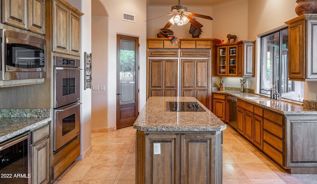 kitchen featuring wine cooler, sink, built in appliances, a center island, and light stone countertops