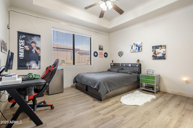 bedroom featuring a tray ceiling, ceiling fan, and light hardwood / wood-style floors