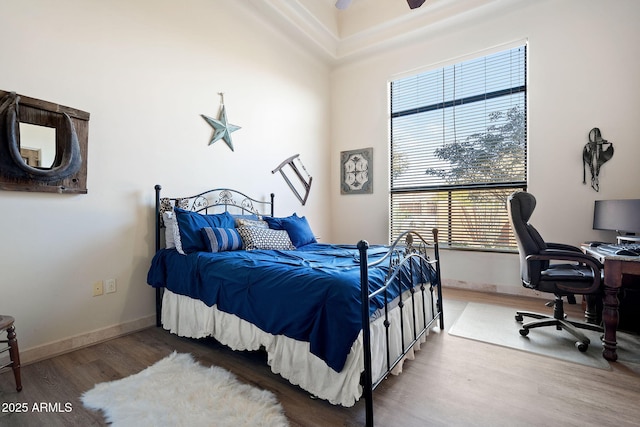 bedroom with multiple windows, wood-type flooring, and ceiling fan