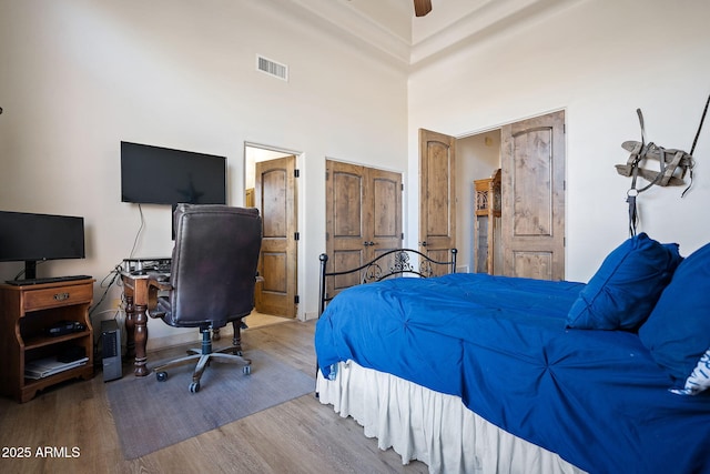 bedroom featuring a high ceiling, hardwood / wood-style floors, and ceiling fan