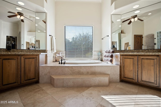 bathroom with tiled tub, vanity, tile patterned floors, and ceiling fan