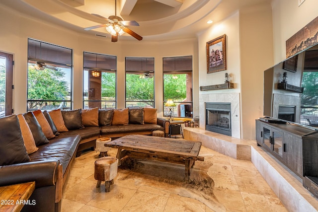 living room with a tiled fireplace, coffered ceiling, and ceiling fan