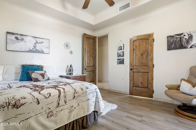 bedroom featuring a raised ceiling, ceiling fan, and light hardwood / wood-style floors