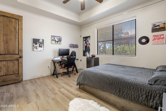 bedroom with a tray ceiling, light hardwood / wood-style flooring, and ceiling fan