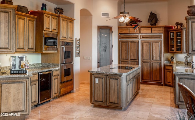 kitchen featuring sink, stainless steel appliances, a center island, wine cooler, and light stone counters