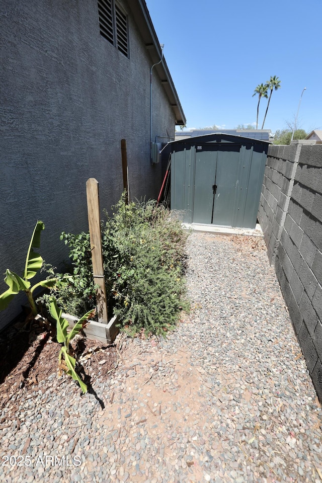 711 W El Alba Way, Chandler, AZ 85225 - view of side of home featuring stucco siding, fence, a storage shed, and an outbuilding