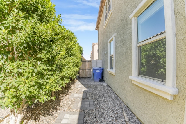 view of side of property with stucco siding, a gate, and fence