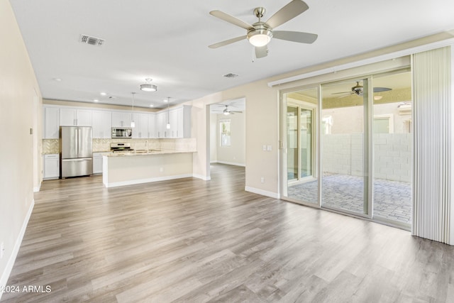unfurnished living room featuring a ceiling fan, light wood-style floors, a sink, baseboards, and recessed lighting
