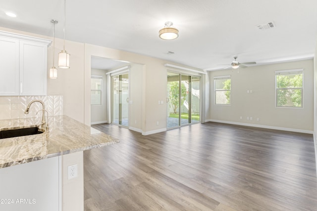 unfurnished living room featuring a sink, a ceiling fan, baseboards, and wood finished floors