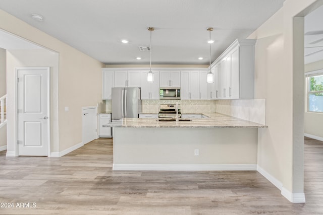 kitchen with appliances with stainless steel finishes, a peninsula, backsplash, white cabinetry, and light stone countertops