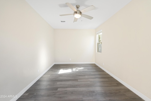 empty room with ceiling fan, dark wood finished floors, and baseboards
