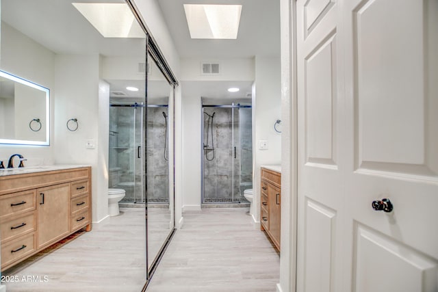 7300 N Dreamy Draw Dr Unit 202, Phoenix, AZ 85020 - bathroom with a skylight, vanity, a stall shower, wood finished floors, and recessed lighting