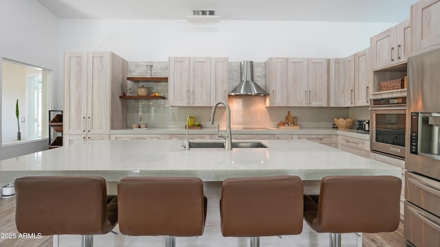4073 E Stable Ct, Gilbert, AZ 85297 - kitchen featuring stainless steel appliances, a sink, open shelves, wall chimney range hood, and a breakfast bar area