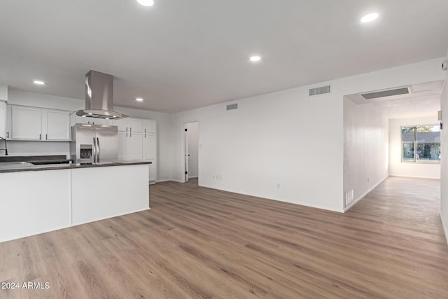 kitchen with stainless steel fridge, light wood-type flooring, extractor fan, sink, and white cabinetry