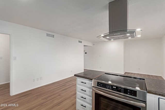 kitchen with island exhaust hood, white cabinetry, stove, and light wood-type flooring