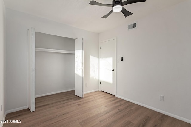 unfurnished bedroom with ceiling fan, a closet, and hardwood / wood-style flooring