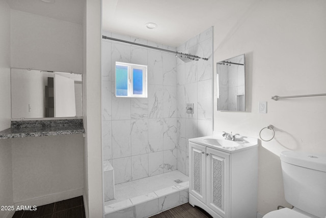 bathroom with toilet, vanity, and tiled shower