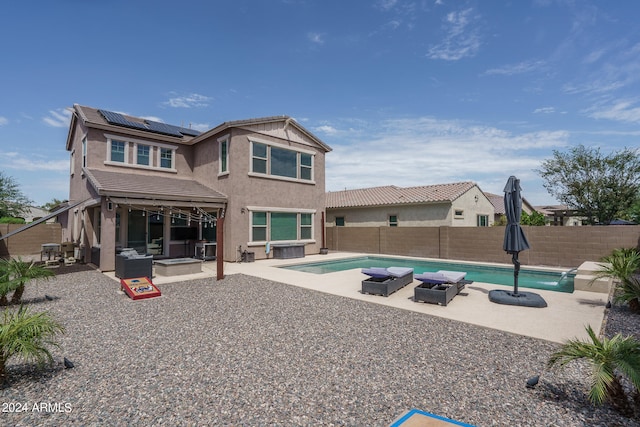 rear view of house with a fenced in pool, an outdoor living space, a patio area, and solar panels