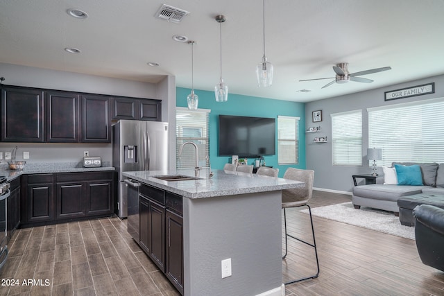 kitchen featuring a center island with sink, a kitchen bar, sink, hardwood / wood-style flooring, and ceiling fan