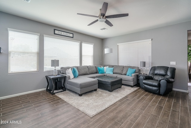 living room featuring plenty of natural light, ceiling fan, and dark wood-type flooring