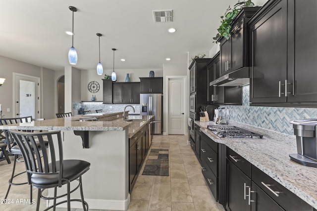 kitchen featuring appliances with stainless steel finishes, a kitchen breakfast bar, tasteful backsplash, a spacious island, and pendant lighting