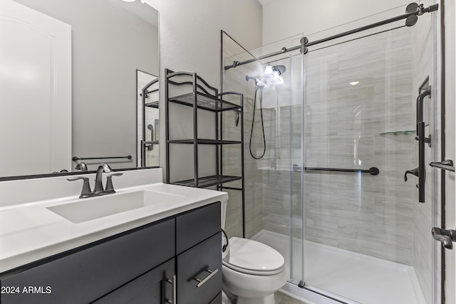 bathroom featuring a shower with door, vanity, and toilet