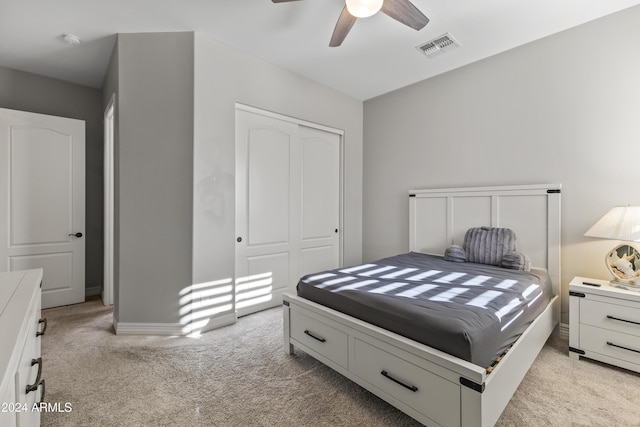 bedroom with a closet, ceiling fan, and light colored carpet