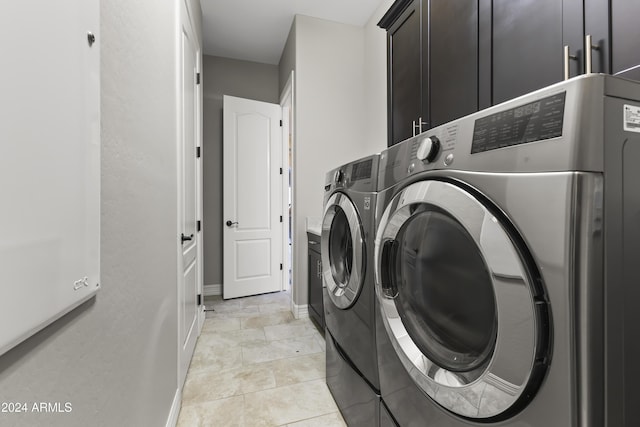 laundry area featuring separate washer and dryer, light tile patterned floors, and cabinets