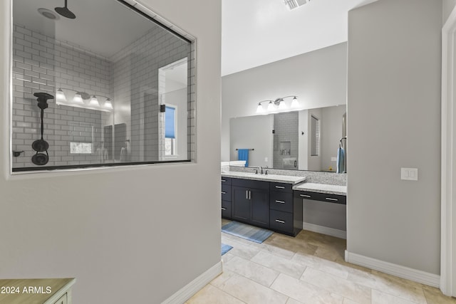 bathroom featuring tile patterned flooring, vanity, and a tile shower