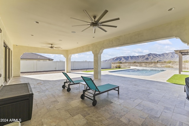 view of patio / terrace featuring a mountain view, ceiling fan, and a fenced in pool