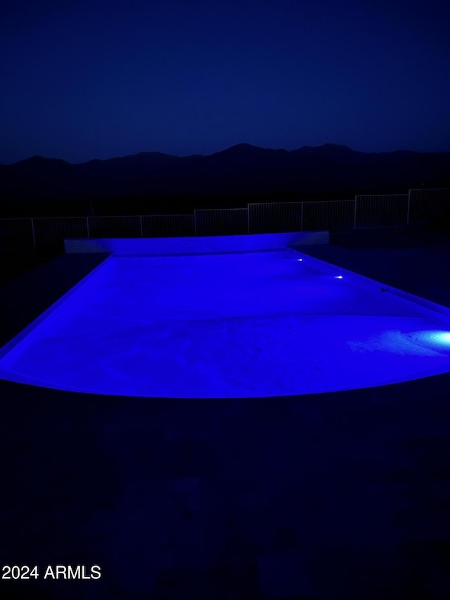 pool at night featuring a mountain view