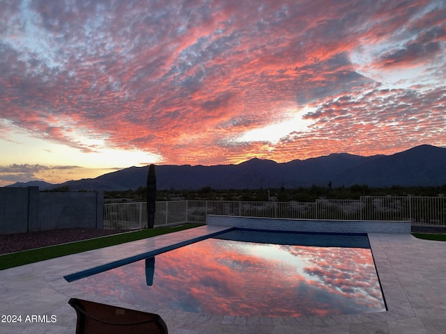 pool at dusk featuring a mountain view