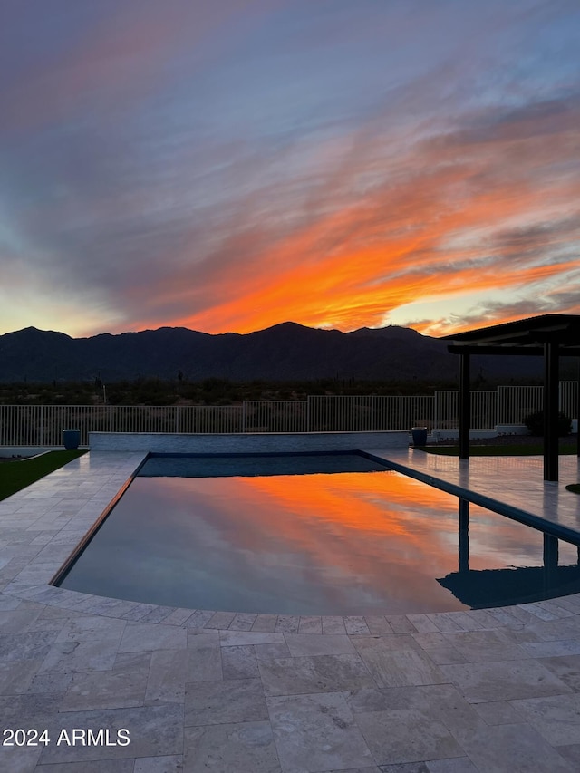 pool at dusk with a mountain view and a patio