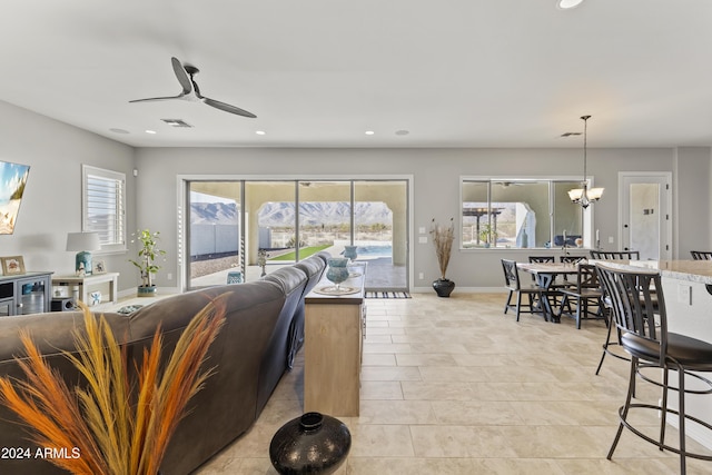 tiled living room with ceiling fan with notable chandelier and a healthy amount of sunlight