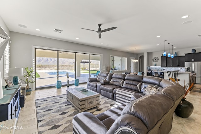 living room with light tile patterned floors and ceiling fan with notable chandelier