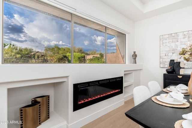 dining room featuring a glass covered fireplace and wood finished floors