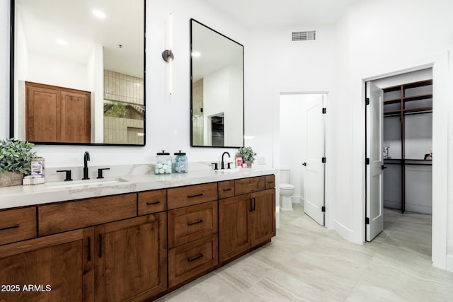 bathroom with toilet and double vanity