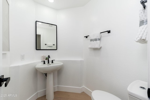 half bath featuring toilet, wood finished floors, and baseboards